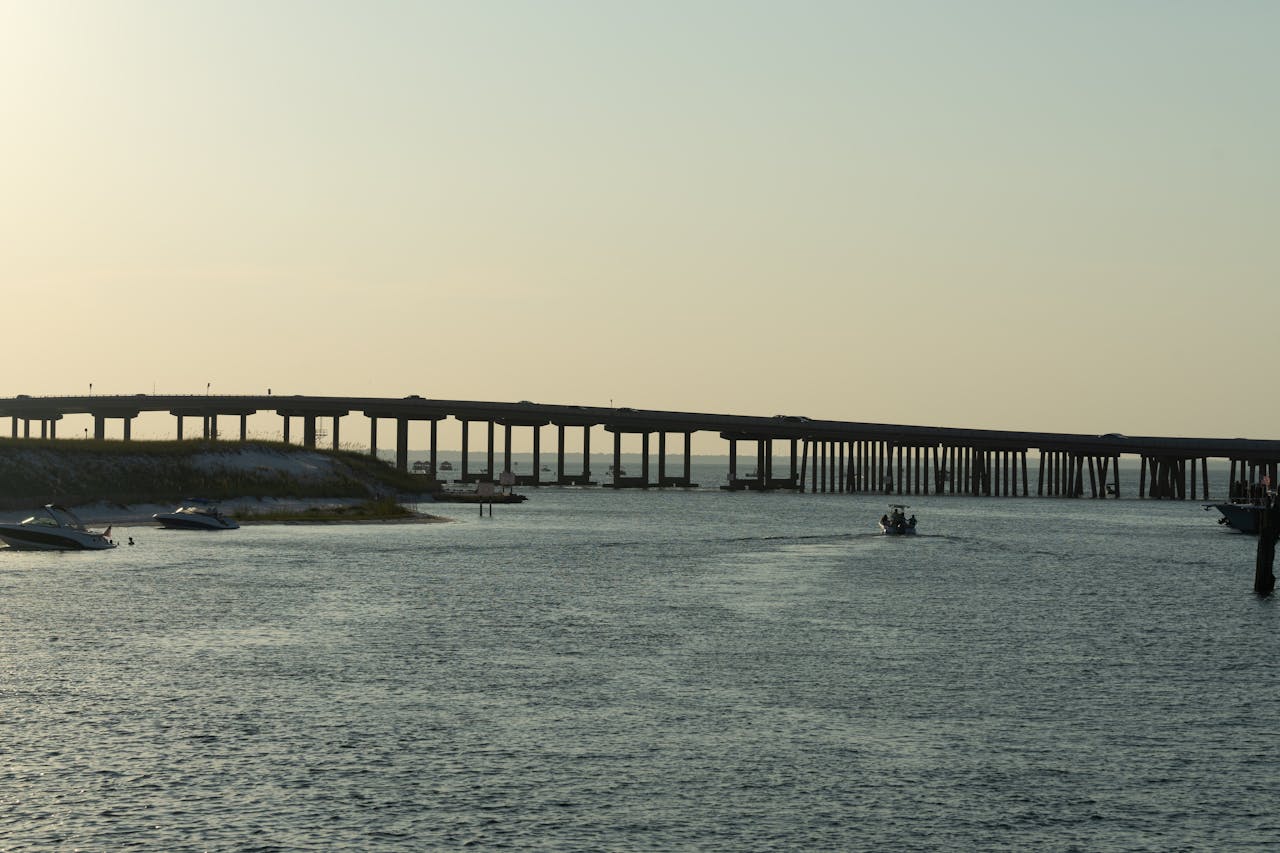 The Art of Drawing Readers In: Your attractive post title goes here Peaceful scene of Destin Bridge over calm waters at sunset with boats nearby.